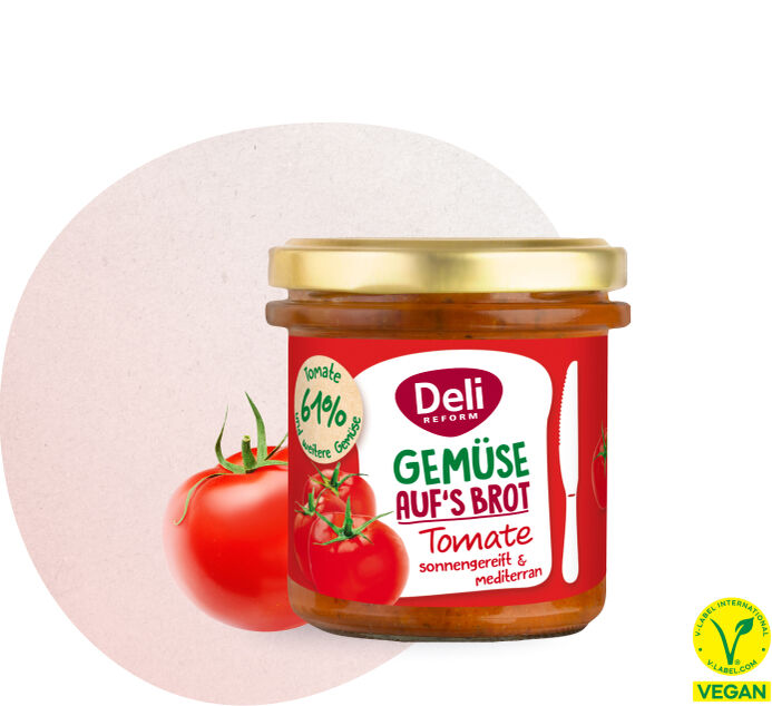 Glas mit Deli Reform Bio Gemüseaufstrich Tomate vor roter Tomate und Petersilienblatt
