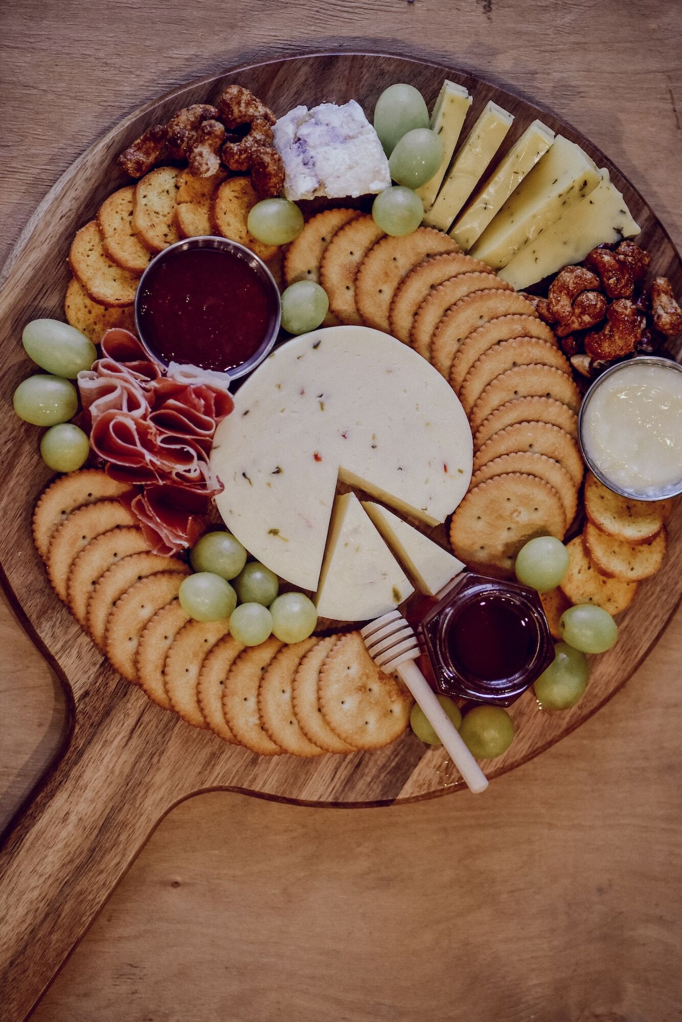 Ein Charcuterie-Board mit Käse, Räucherschinken, Trauben, Dips und Crackern