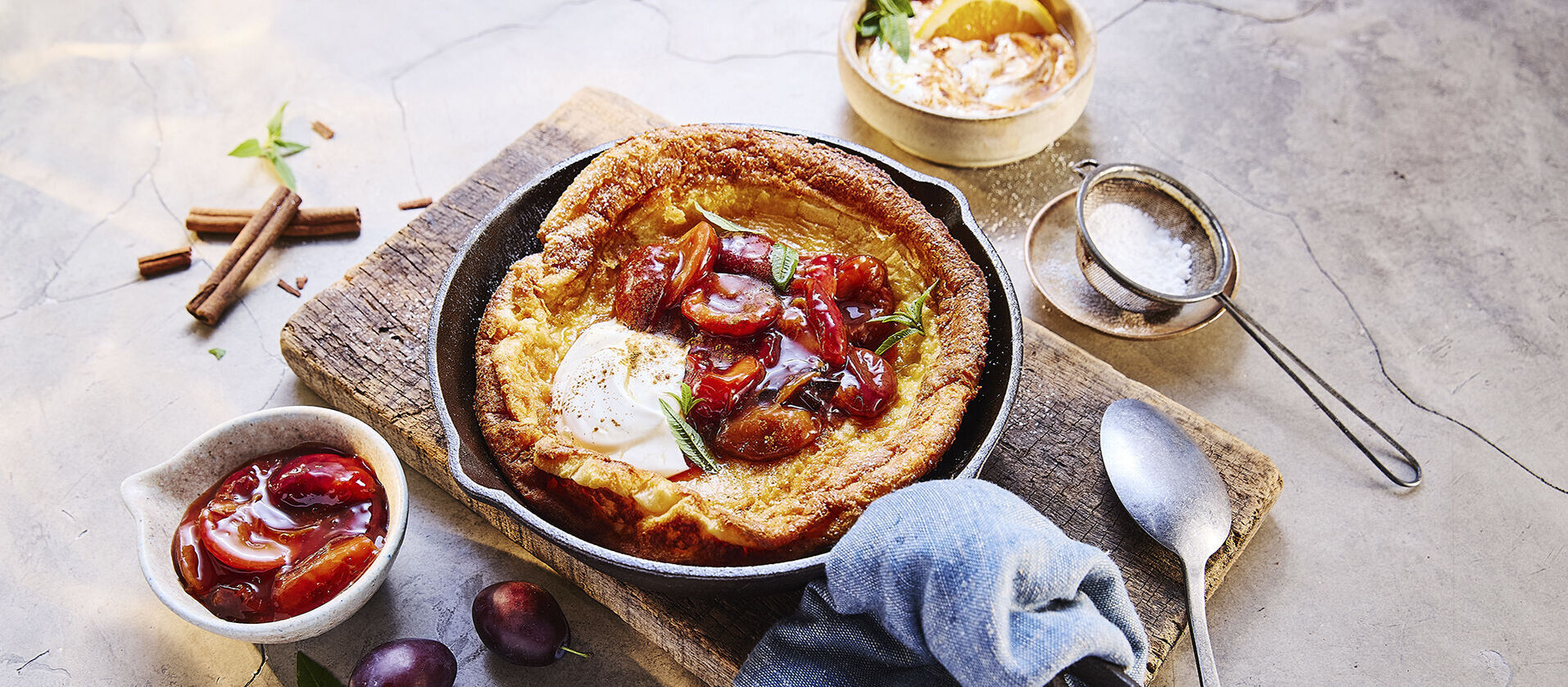 Ein frisch gebackener Ofenpfannkuchen, mit Pflaumen und Zimtcreme garniert.