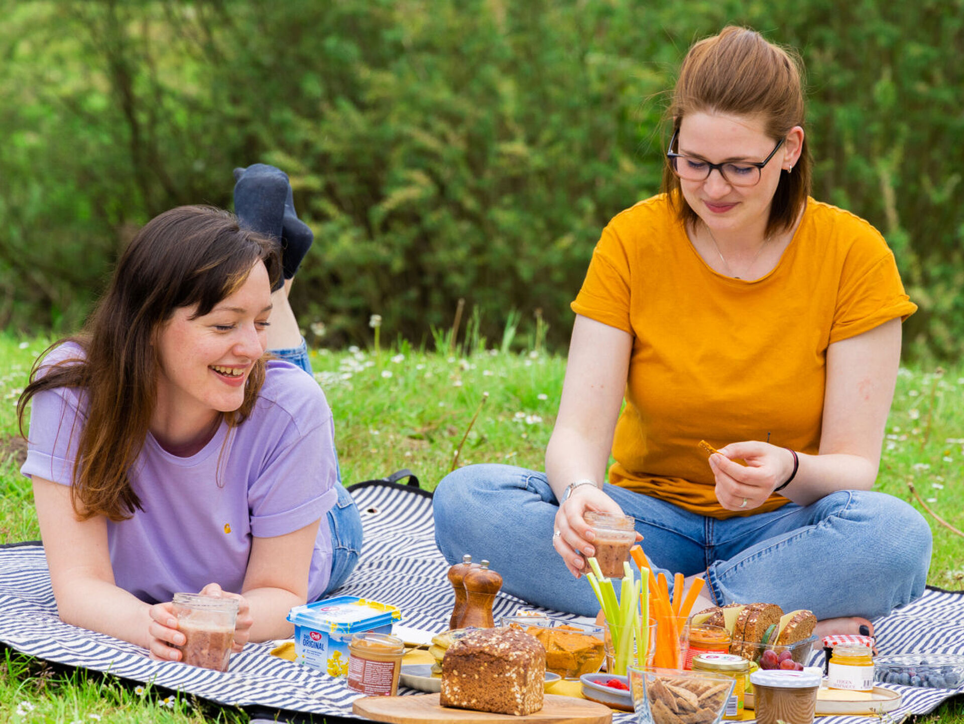 Zwei Frauen picknicken auf einer Decke auf einer Wiese