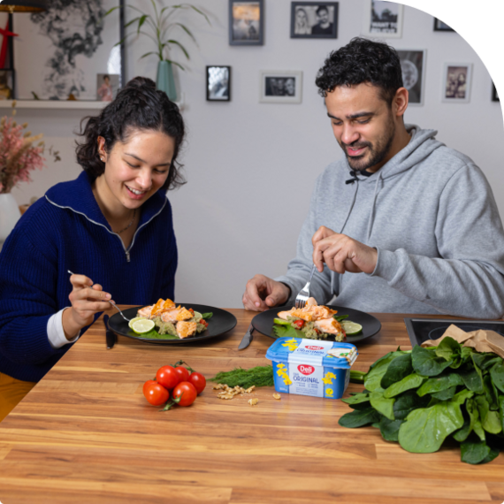 Eine Frau und ein Mann essen gemeinsam ein gesundes Gericht mit Lachs.