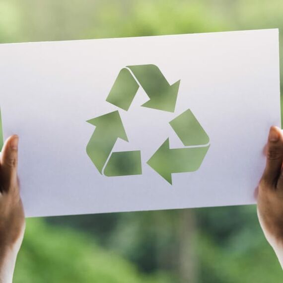 Zwei Hände halten ein Schild hoch, auf dem ein Recycling-Symbol abgebildet ist