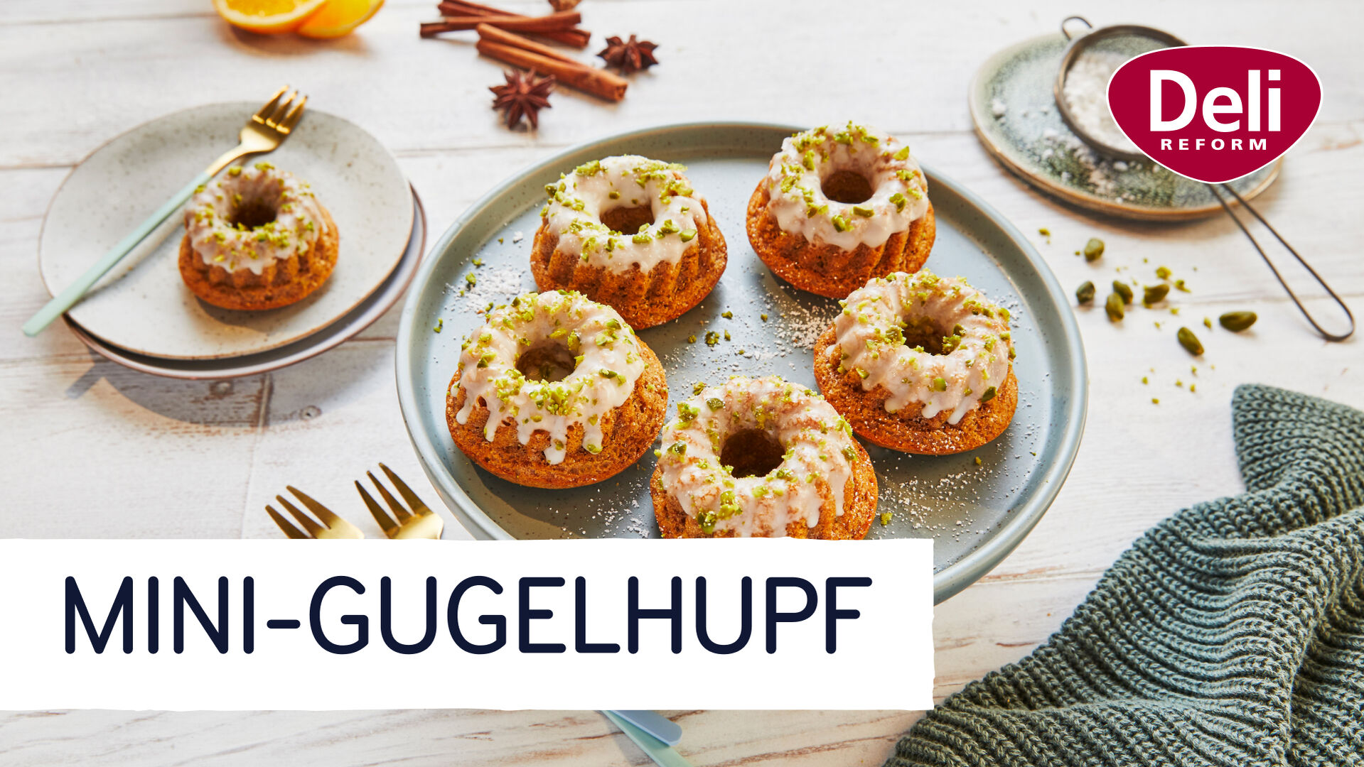 Fünf kleine Mini-Gugelhupf-Kuchen mit Glasur und Pistazienstücken stehen schön angerichtet auf einem Teller. Darunter steht der Videotitel „Mini-Gugelhupf“. Oben rechts im Bild ist das Logo der Marke Deli Reform.