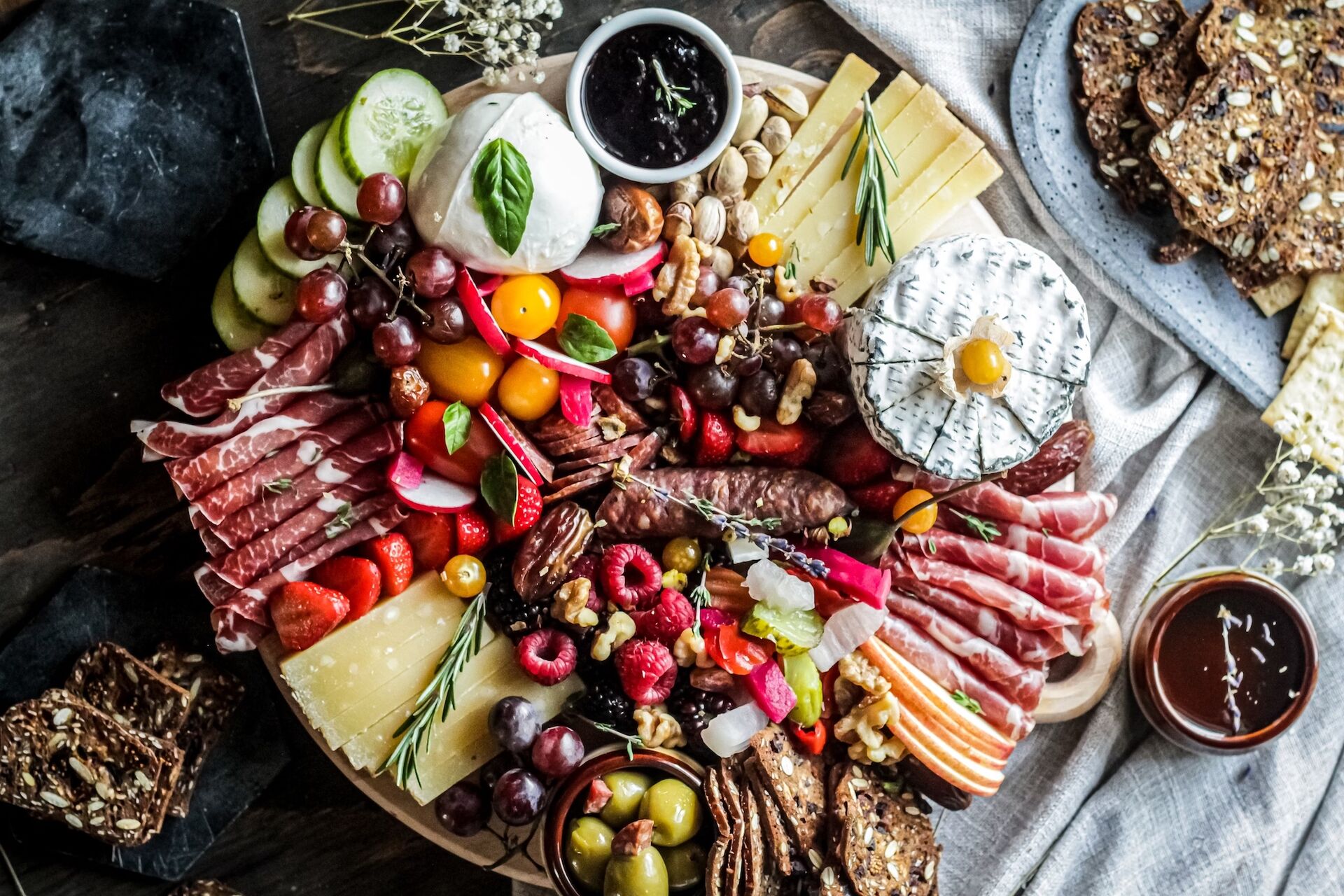 Ein Charcuterie-Board mit Käse, Räucherschinken, Aufschnitt, Gemüse, Obst und Brot