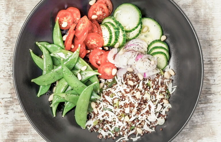 Bowl mit Tomaten, Zuckerschoten, Gurkenscheiben, Radieschenscheiben und Quinoa.