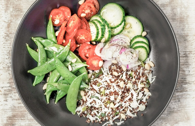 Bowl mit Tomaten, Zuckerschoten, Gurkenscheiben, Radieschenscheiben und Quinoa.
