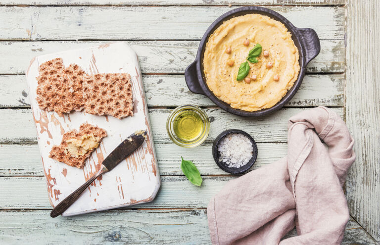 Knäckebrot und kleine Schüsseln mit Humus, Öl und Salz