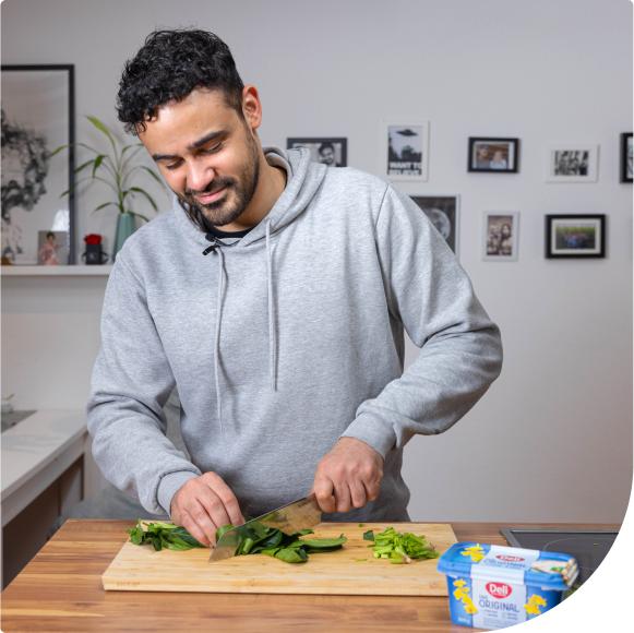 Ein junger Mann schneidet Gemüse, um besser zu essen.